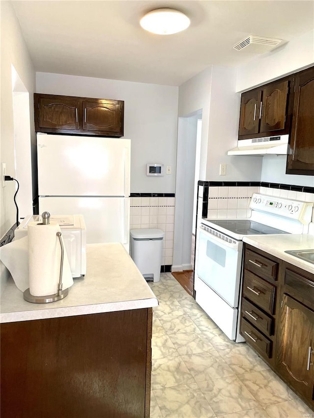 kitchen with dark brown cabinets, white appliances, and tile walls