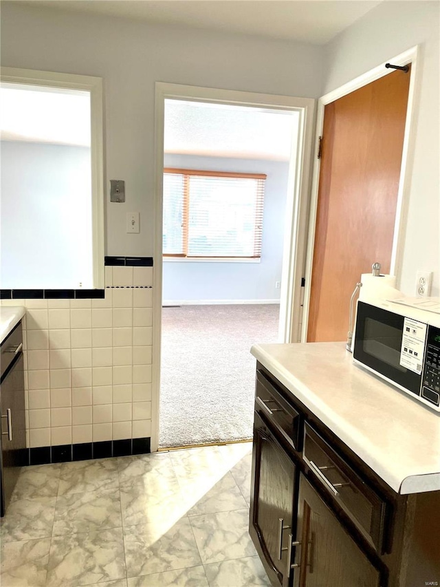 kitchen featuring tile walls and dark brown cabinets