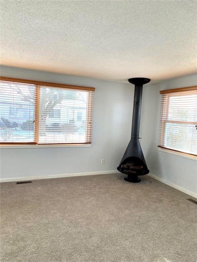 unfurnished living room with a wood stove and carpet floors