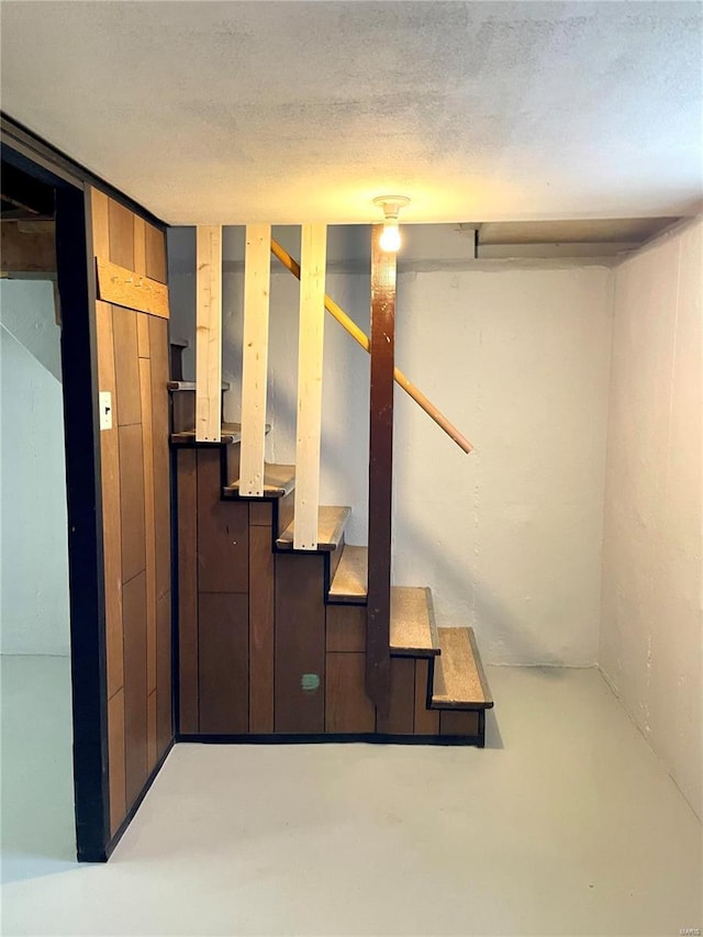 stairway featuring concrete floors and a textured ceiling