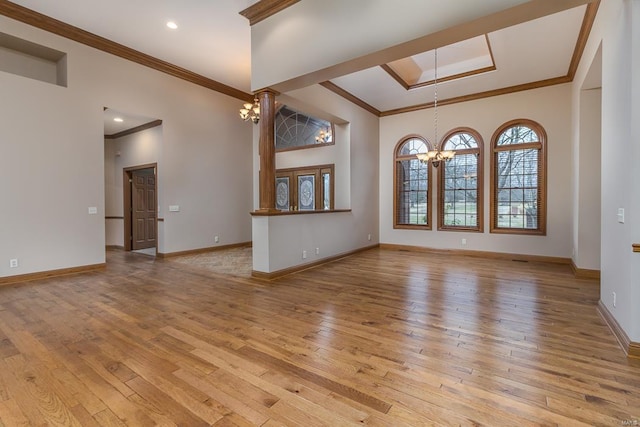 unfurnished room with a raised ceiling, a notable chandelier, crown molding, and light hardwood / wood-style floors