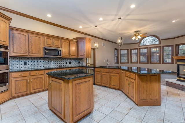 kitchen with stainless steel appliances, a fireplace, hanging light fixtures, a kitchen island, and sink