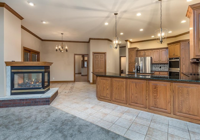 kitchen with pendant lighting, stainless steel appliances, backsplash, a brick fireplace, and light tile patterned floors