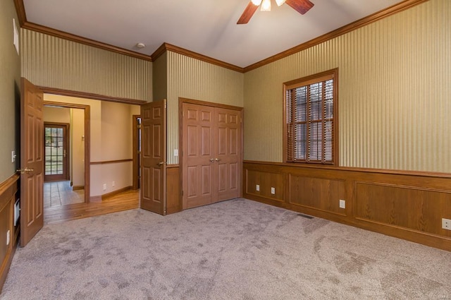 unfurnished bedroom with ceiling fan, a closet, light carpet, and ornamental molding