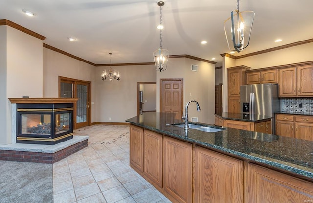 kitchen with a notable chandelier, pendant lighting, sink, a multi sided fireplace, and stainless steel fridge