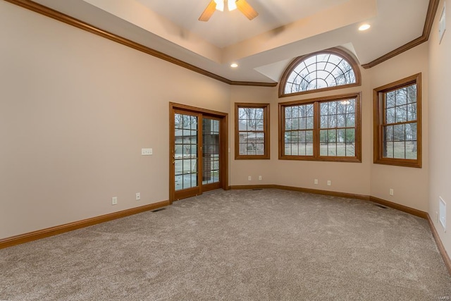 carpeted spare room with ceiling fan, crown molding, and a tray ceiling