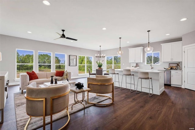 living room with a healthy amount of sunlight, dark wood-type flooring, sink, and ceiling fan with notable chandelier