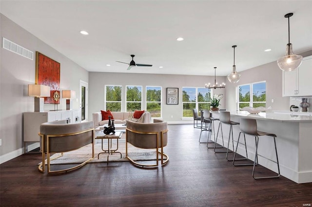 living room with ceiling fan with notable chandelier and dark hardwood / wood-style floors