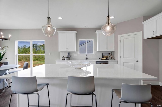 kitchen featuring a kitchen island, white cabinetry, tasteful backsplash, and hanging light fixtures