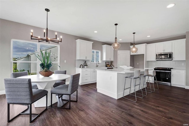 kitchen with stainless steel appliances, white cabinets, decorative light fixtures, tasteful backsplash, and a kitchen island