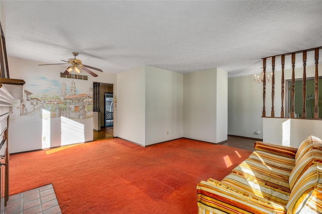 unfurnished living room with a textured ceiling, carpet floors, and ceiling fan with notable chandelier