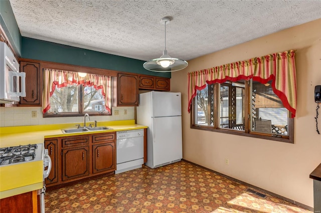 kitchen with white appliances, visible vents, dark floors, light countertops, and a sink