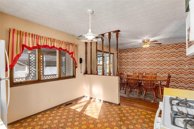 kitchen featuring white appliances, baseboards, visible vents, tile patterned floors, and a textured ceiling