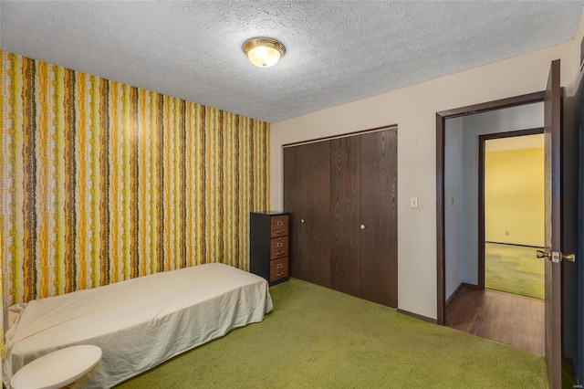 bedroom with a textured ceiling, baseboards, a closet, and carpet flooring