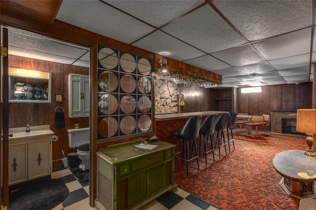 bar with wooden walls, a sink, and tile patterned floors