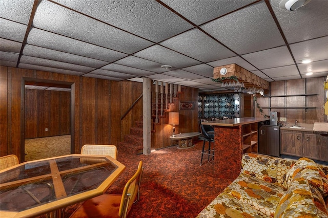 bar featuring stairs, a bar, a sink, and wooden walls