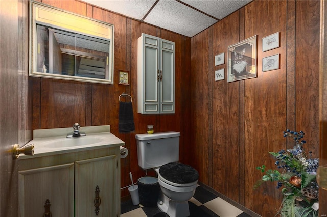 bathroom with wooden walls, toilet, and vanity