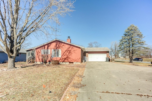 view of front facade with an attached garage, a chimney, and concrete driveway