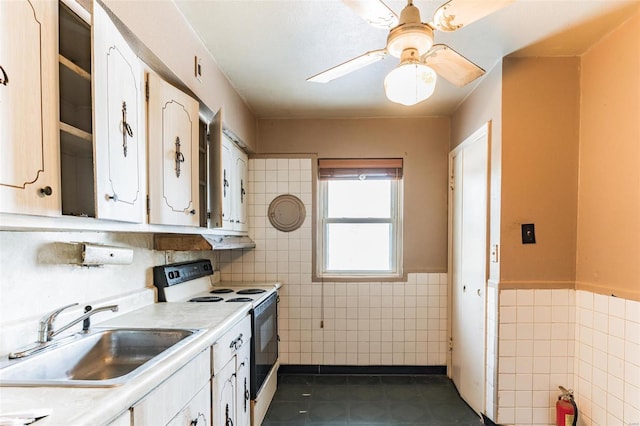 kitchen with sink, tile walls, white electric stove, and white cabinets