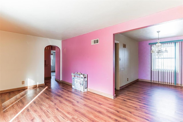 spare room with hardwood / wood-style floors and a chandelier