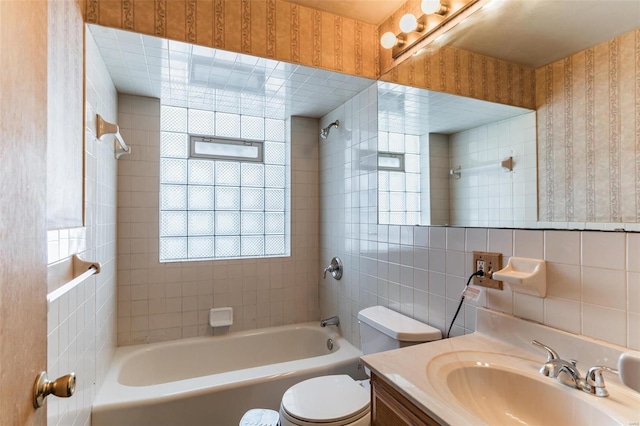 full bathroom featuring tiled shower / bath combo, vanity, tasteful backsplash, tile walls, and toilet