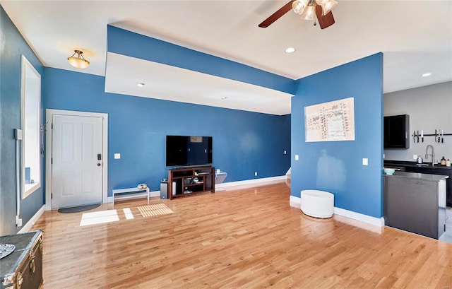 living room featuring ceiling fan, light hardwood / wood-style floors, and sink