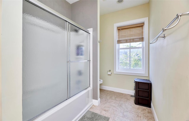 bathroom with toilet and shower / bath combination with glass door