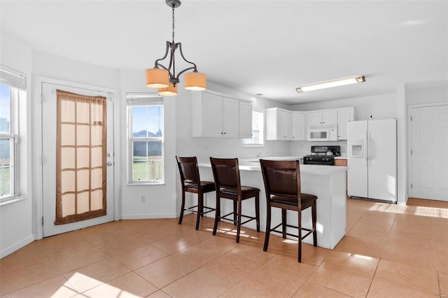 kitchen with white appliances, decorative light fixtures, white cabinetry, kitchen peninsula, and a notable chandelier