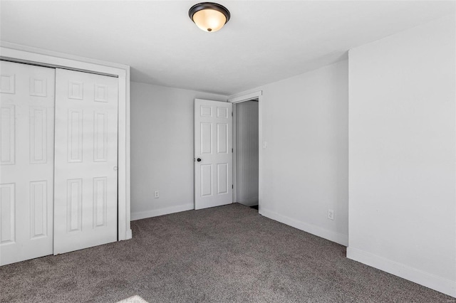 unfurnished bedroom with a closet and dark colored carpet