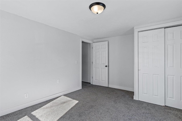 unfurnished bedroom with dark colored carpet and a closet