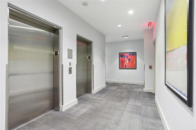 corridor featuring carpet, elevator, and baseboards