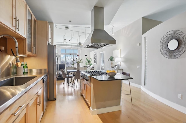 kitchen with island exhaust hood, a breakfast bar area, stainless steel countertops, appliances with stainless steel finishes, and a sink