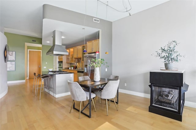 dining area featuring visible vents, light wood-style flooring, and baseboards