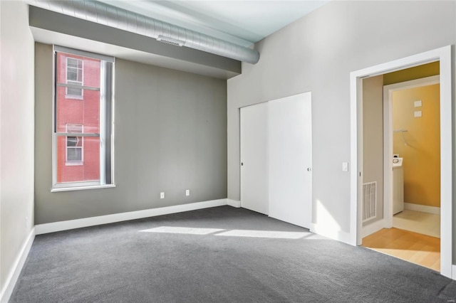 carpeted empty room featuring washer / dryer, baseboards, and visible vents