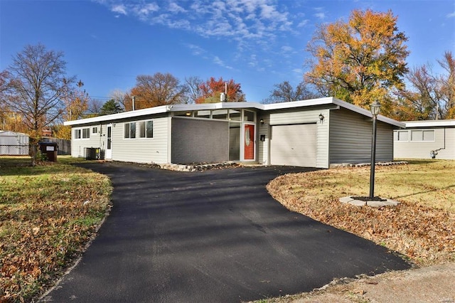 view of front facade featuring central air condition unit, a front yard, and a garage