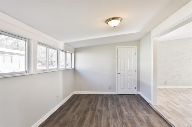 unfurnished room featuring lofted ceiling and dark hardwood / wood-style floors