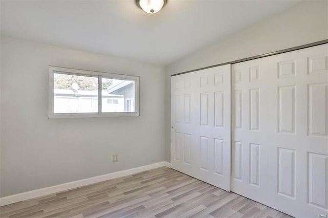 unfurnished bedroom with a closet, vaulted ceiling, and light hardwood / wood-style flooring