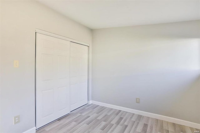 unfurnished bedroom with light hardwood / wood-style flooring and a closet