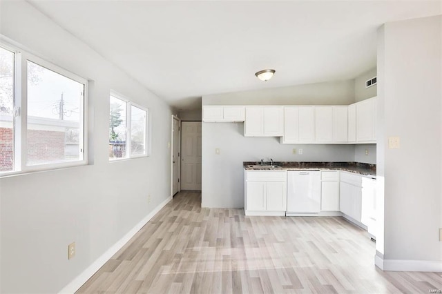 kitchen with dishwasher, vaulted ceiling, white cabinets, light hardwood / wood-style flooring, and sink