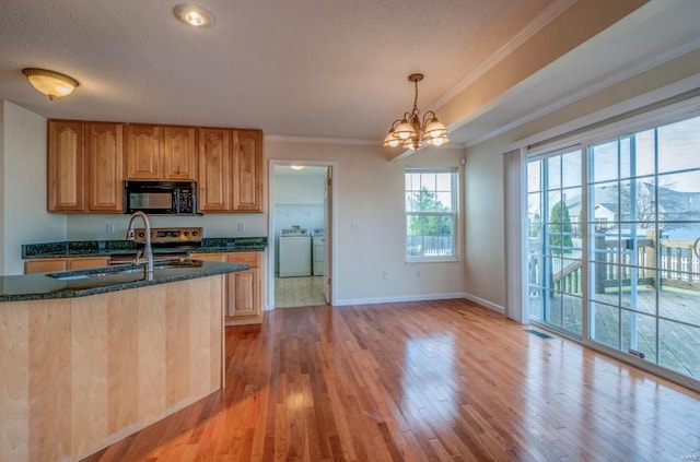 kitchen with stainless steel range with electric cooktop, hanging light fixtures, crown molding, a notable chandelier, and washer and clothes dryer