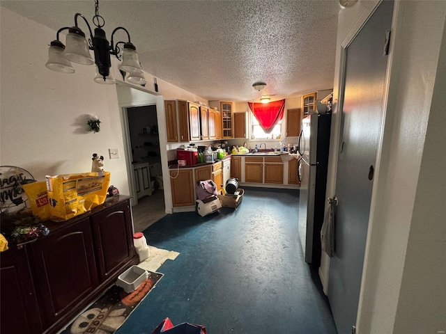 kitchen featuring sink, a chandelier, stainless steel refrigerator, and a textured ceiling