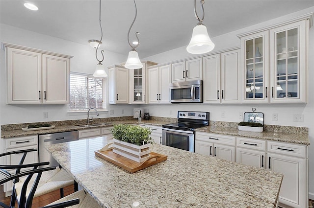 kitchen featuring a center island, decorative light fixtures, white cabinetry, stainless steel appliances, and sink