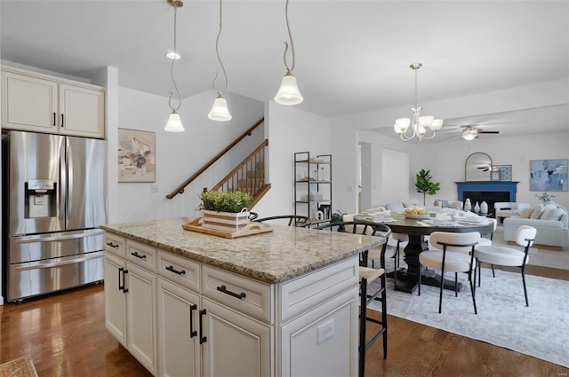 kitchen featuring light stone countertops, pendant lighting, a center island, dark hardwood / wood-style floors, and stainless steel fridge