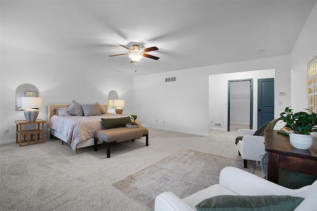 carpeted bedroom with ceiling fan, a walk in closet, and a closet