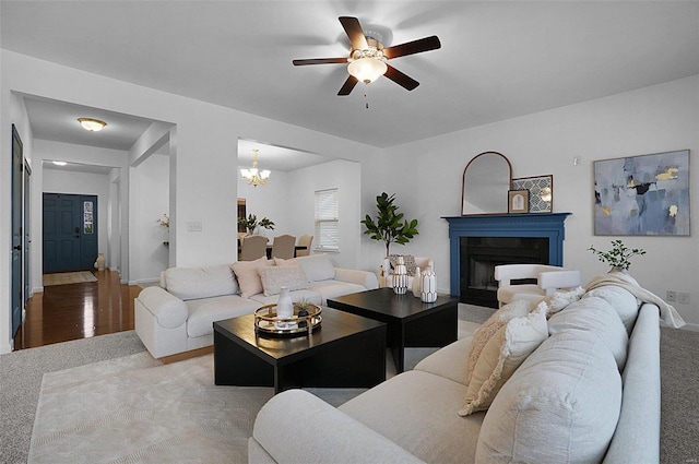 living room with light colored carpet and ceiling fan with notable chandelier