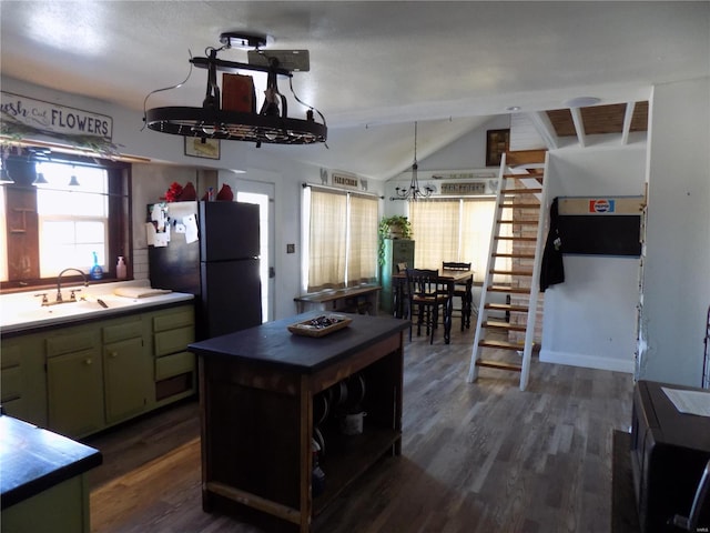 kitchen featuring vaulted ceiling, black fridge, green cabinetry, dark wood-type flooring, and sink