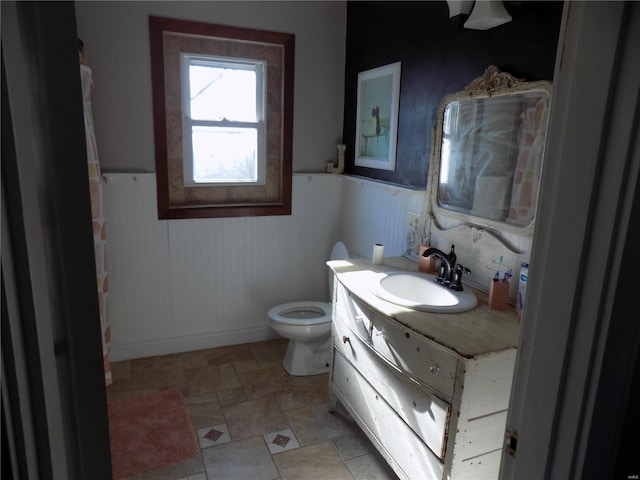 bathroom featuring toilet, wooden walls, and vanity