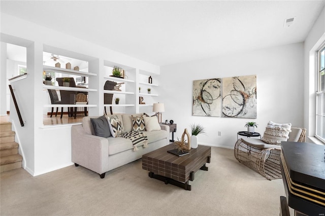 living room featuring built in features and light colored carpet