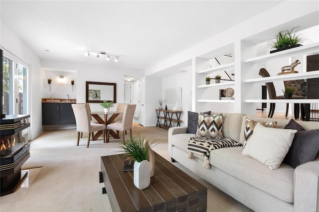 living room featuring a wood stove, built in shelves, a textured ceiling, and carpet floors