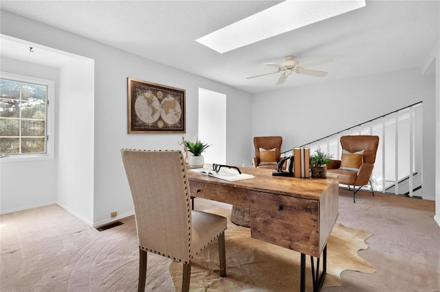 carpeted dining room featuring a skylight and ceiling fan